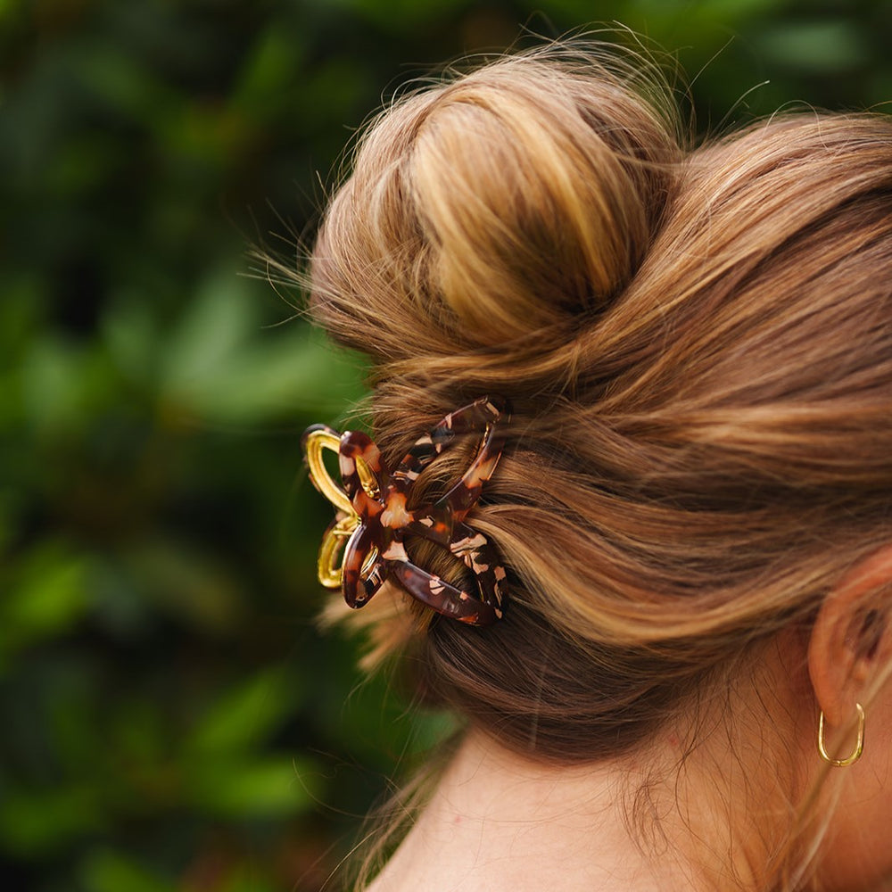 Elegant Emmy metalen vlinder clip in een halve opgestoken haardos, perfect voor dik of krullend haar.