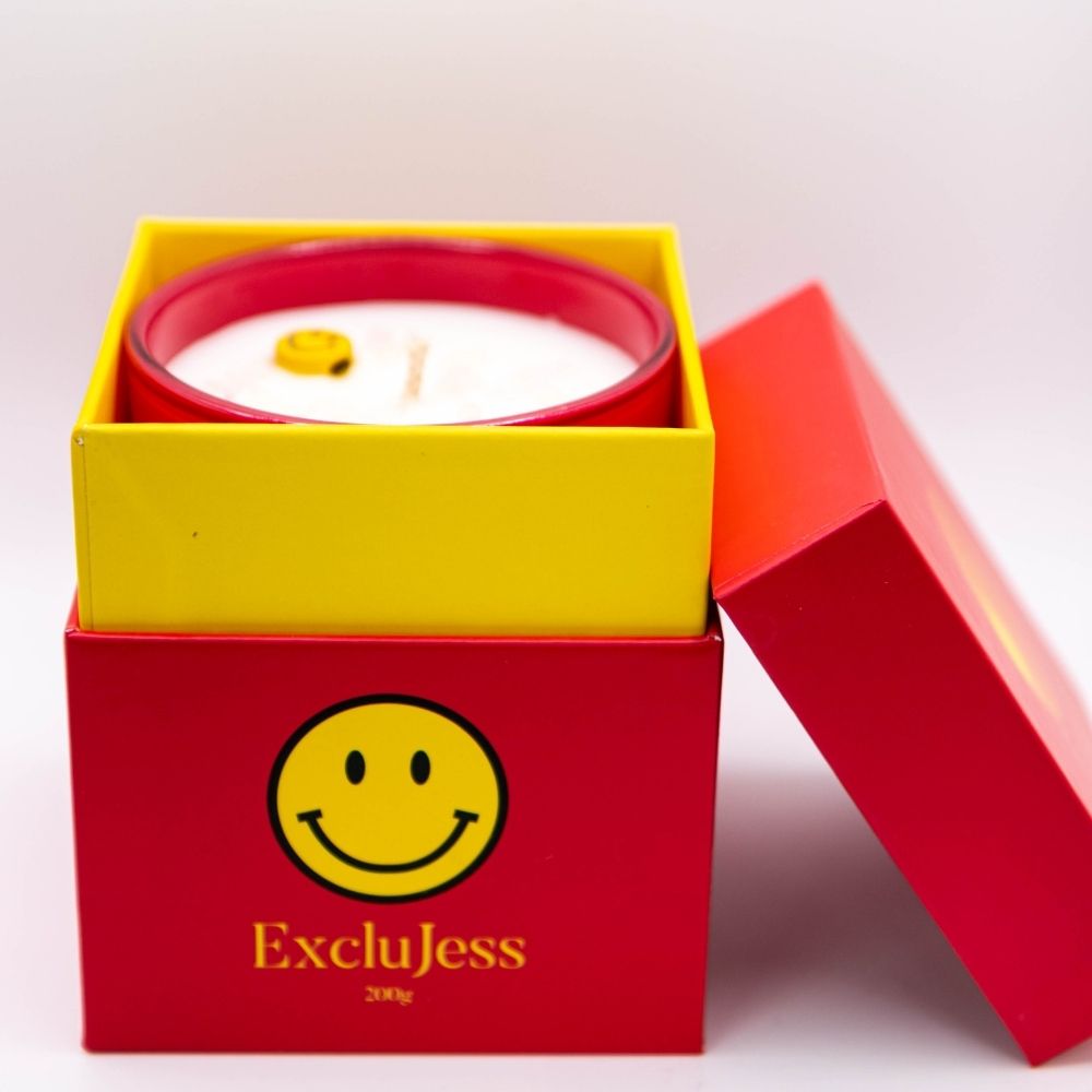 Smiley Kaars in vrolijke verpakking met gele en rode doos, straalt positieve vibes en glimlach uit.