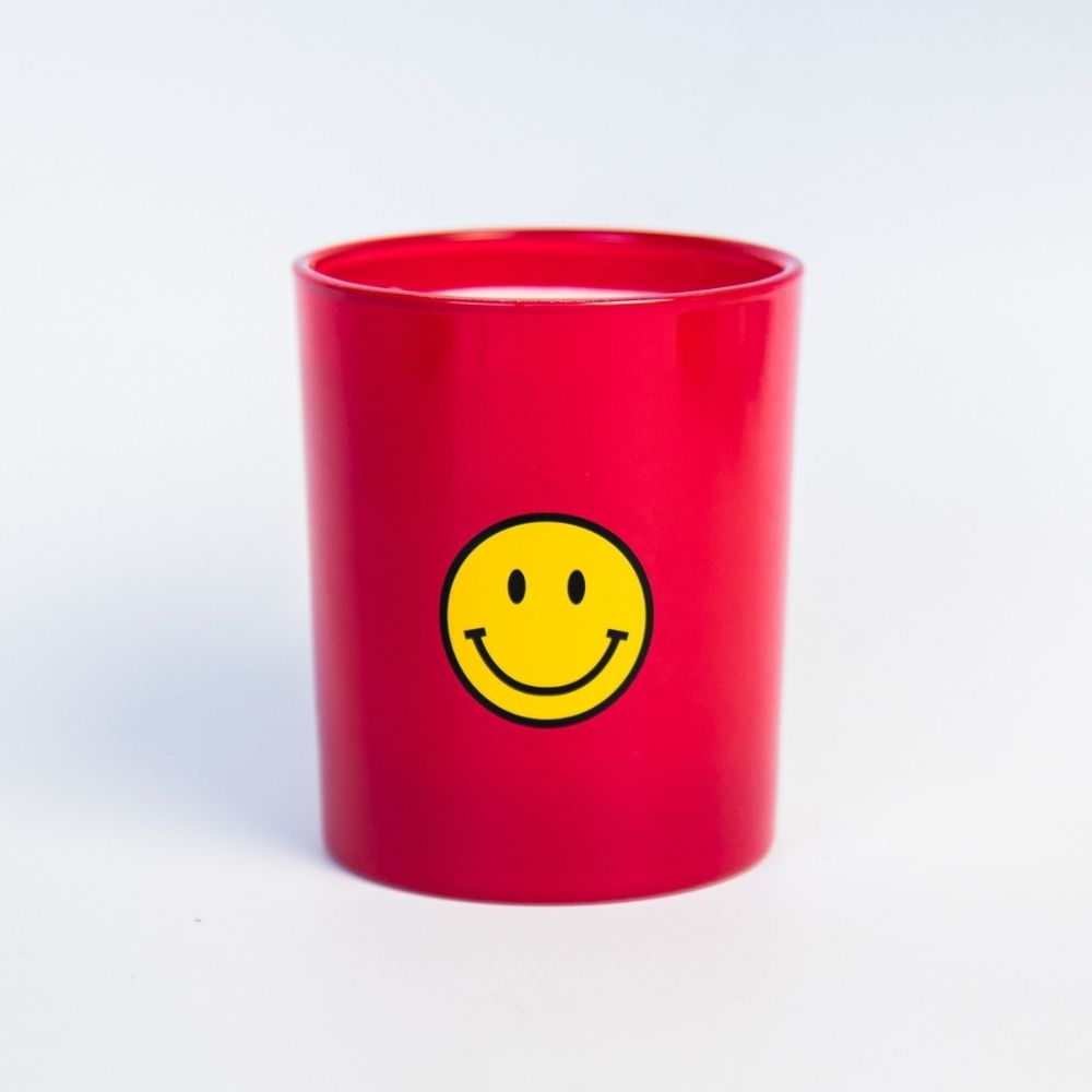 Smiley Kaars in een rode houder met een grote gele glimlach, perfect voor positieve vibes.