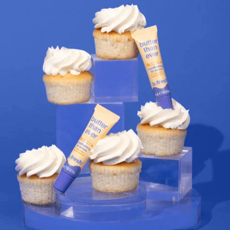 Butter than ever lip serum tubes displayed with vanilla cupcakes on a blue background.